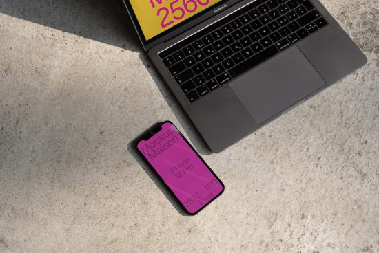 Laptop and smartphone on concrete surface with editable screen mockup, perfect for designers seeking tech-themed graphics templates.