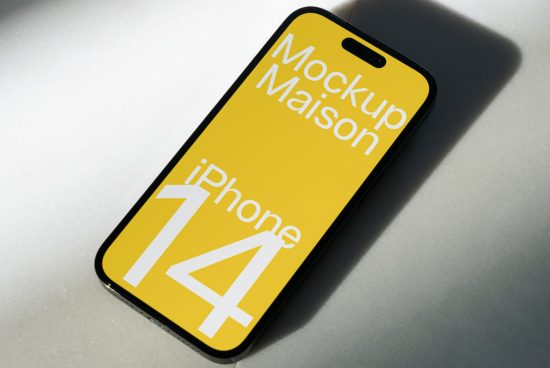 Smartphone mockup on a shaded surface showcasing a yellow screen with text iPhone 14 for digital asset designers.