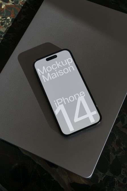 iPhone 14 mockup on laptop and marble surface for digital asset designers, perfect for presentations and showcasing mobile app designs.