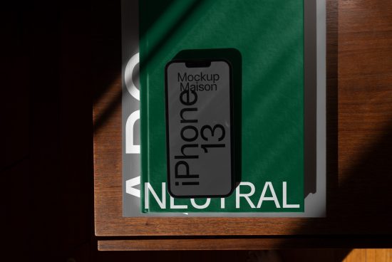 Stylish iPhone 13 mockup on a wooden table with green backdrop, ideal for presentations, digital assets, and showcasing design work for designers.