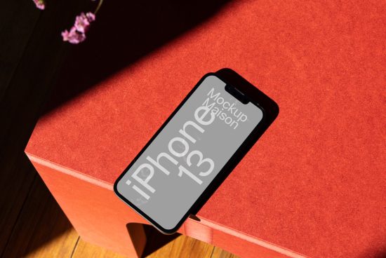 iPhone 13 mockup on red surface with shadow, realistic smartphone design presentation for app and mobile website display.