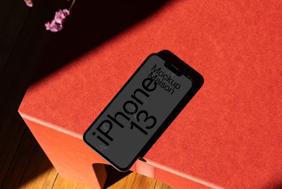 iPhone 13 mockup angled on red surface with moody dark backdrop