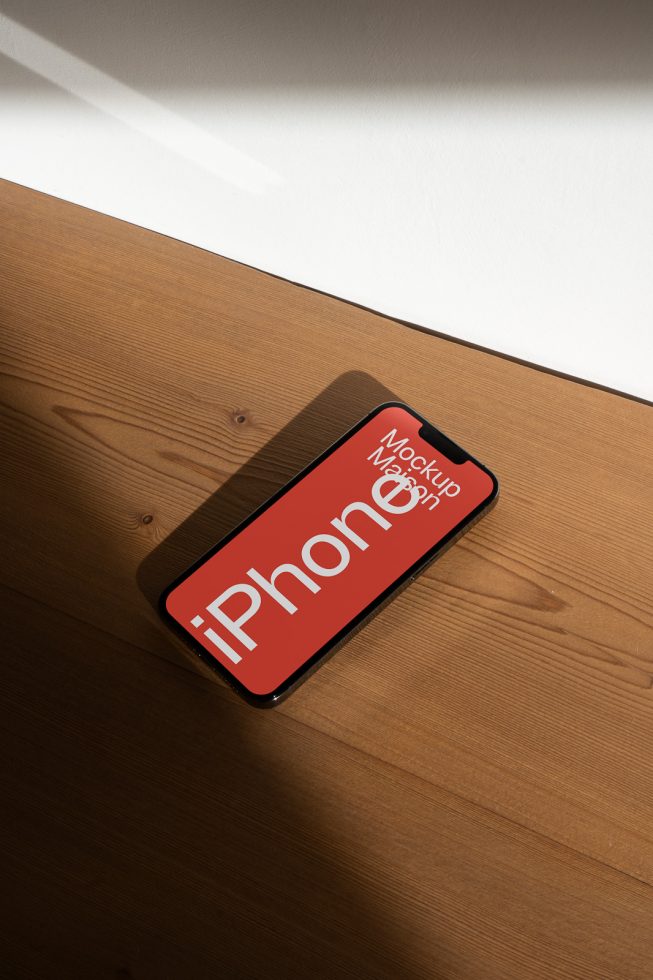 Stylish smartphone mockup on wood surface under natural light, high-resolution digital asset ideal for showcasing app designs.