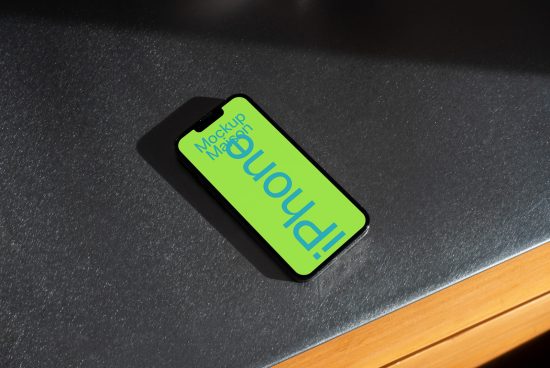 Smartphone on dark surface showing bright green screen mockup, ideal for UI/UX presentation, digital design asset.