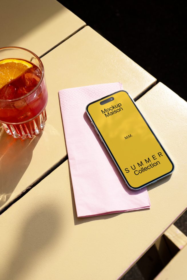 Smartphone mockup on a cafe table with a refreshing drink and napkin perfect for showcasing summer designs, vibrant colors, and mobile graphics.