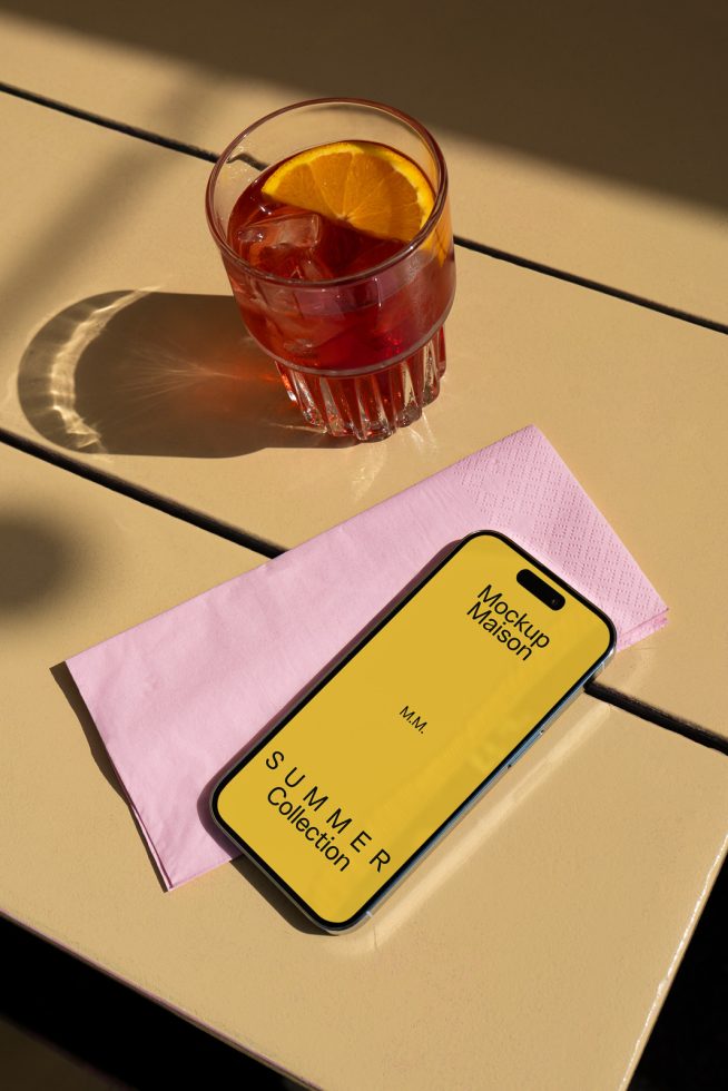 Smartphone screen mockup on table with cocktail, showcasing summer collection design, ideal for graphic presentation in marketing materials.