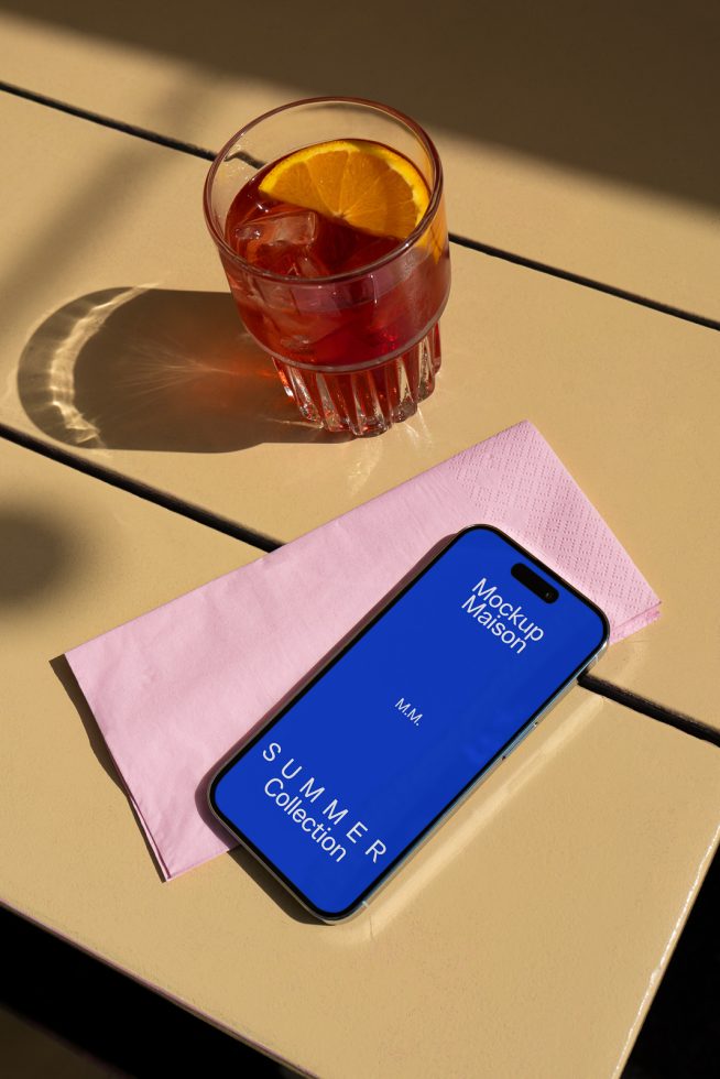 Smartphone screen mockup on a sunny cafe table with a cocktail and napkin, ideal for presenting app designs and interfaces to designers.