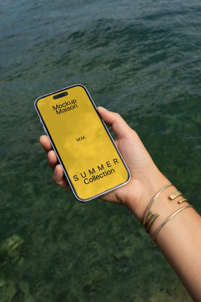 Hand holding smartphone mockup with summer collection design on screen, against water backdrop for designers, editable template.