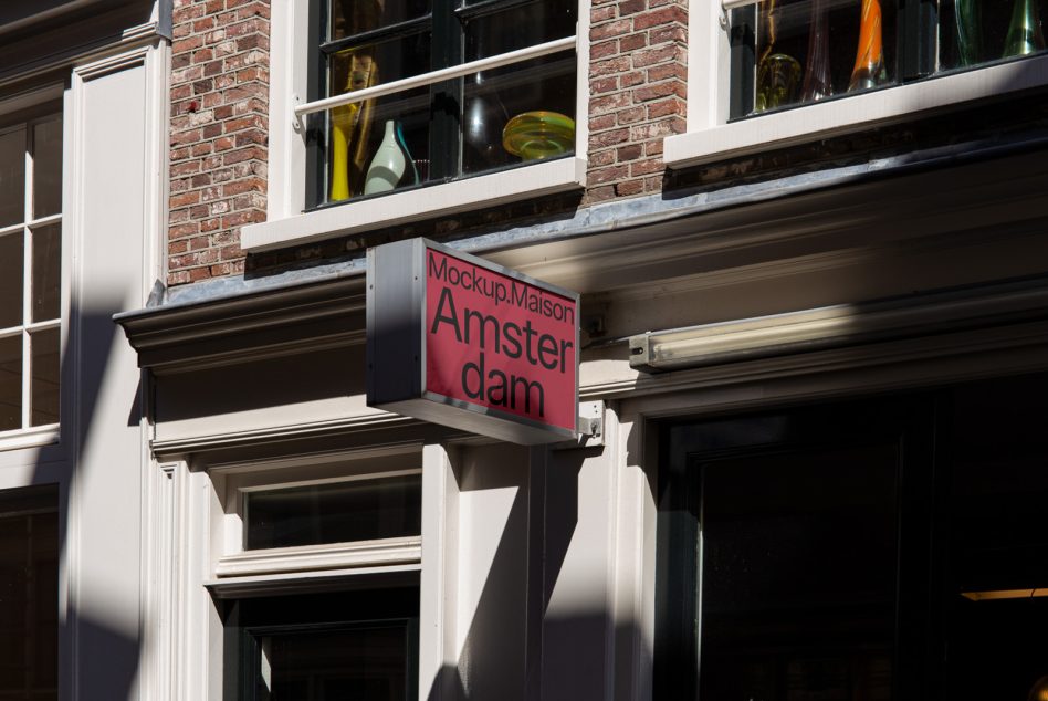 Magenta illuminated sign reading Amsterdam jutting from building storefront edge