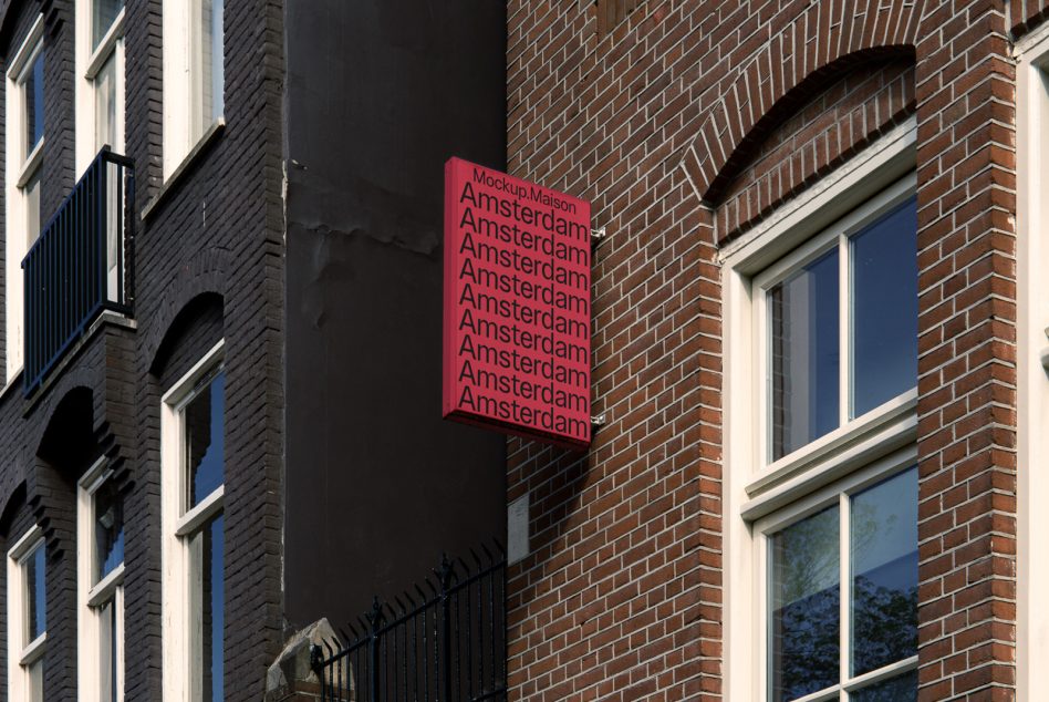 Building-mounted vertical sign in magenta with repeated Amsterdam text on urban storefront