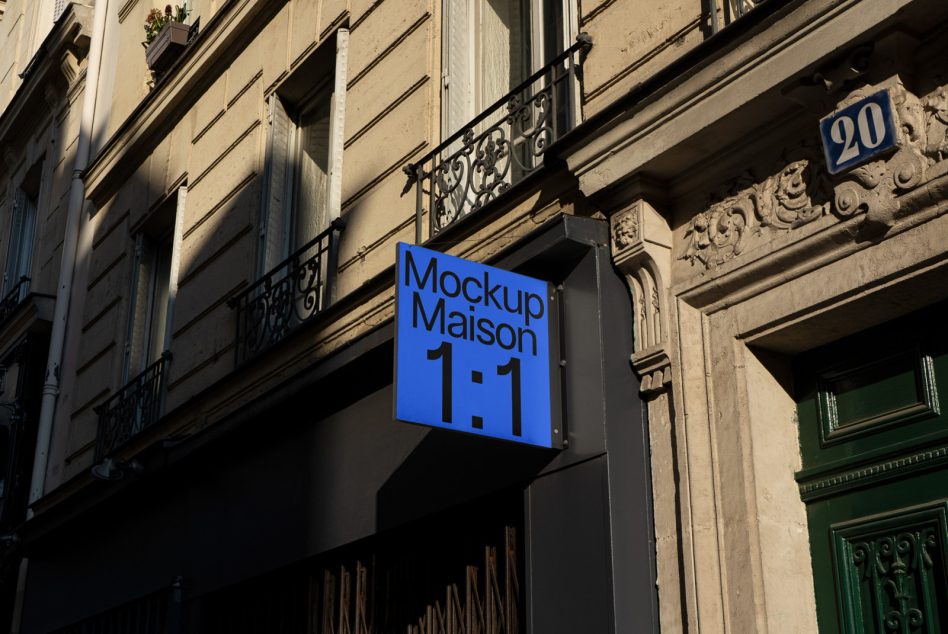 Bright blue illuminated rectangular sign on dark metal bracket above Parisian street entrance
