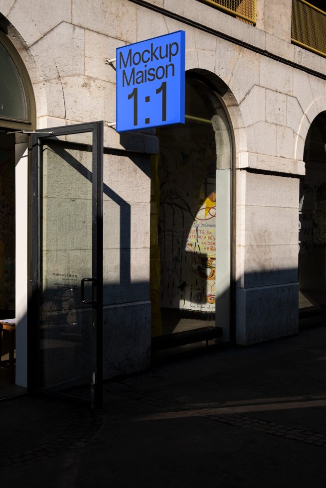 Urban outdoor signage mockup on a blue board hanging above a shopfront in daylight, suitable for presenting branding and design projects.