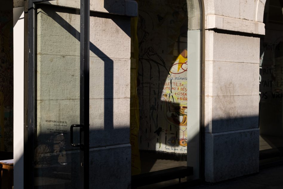 Close up of black metal frame storefront door with stone walls either side