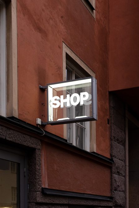 Urban store sign mockup on building corner with reflective glass and modern typography, perfect for branding presentations.