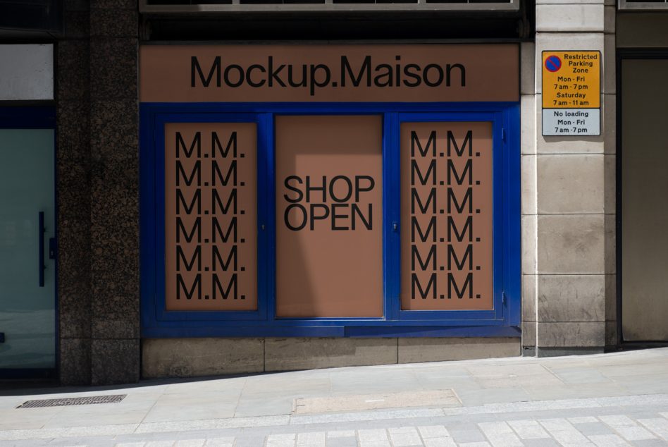 Shop window with blue frame showing tan panels with M.M. pattern, center text says Shop Open