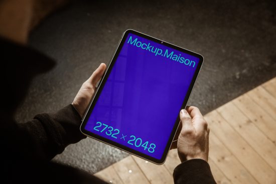 Person holding tablet mockup with blue screen for designers, displaying resolution 2732x2048, ideal for digital design displays.