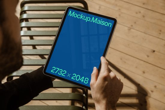 Person holding a tablet with a blue screen mockup showing dimensions 2732x2048, ideal for designers creating digital assets.