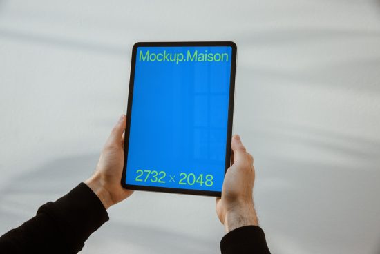 Digital tablet mockup held in hands with a blue screen display and resolution text, ideal for app design presentation.