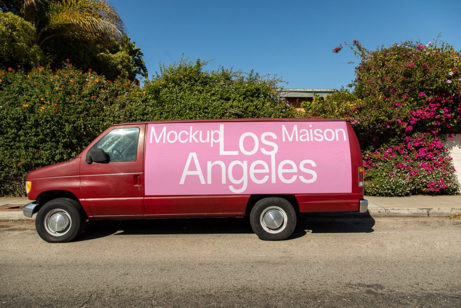 Vehicle wrap mockup on a red van with bold typography showcasing design space, parked in an outdoor setting with greenery in the background.