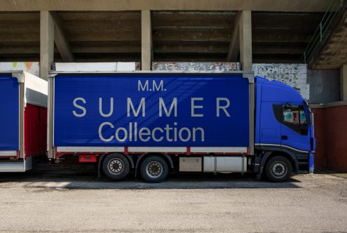 Blue delivery truck with bold 'SUMMER Collection' advertisement, under a bridge, urban logistics theme, perfect for mockup designs.