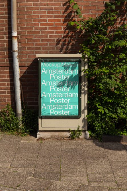 Street poster mockup on a utility box against a brick wall with greenery, showcasing design display in urban setting for graphic designers.