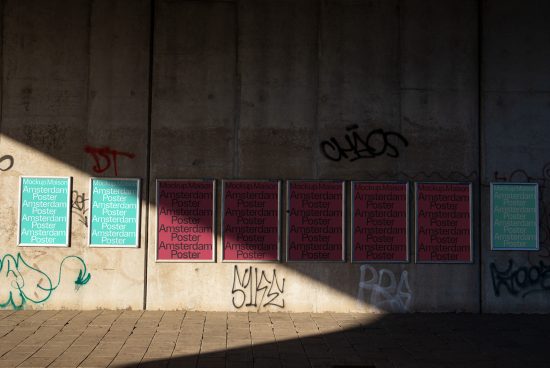 Urban street wall with sunlight casting shadows, adorned with graffiti and aligned poster mockups for design presentations.