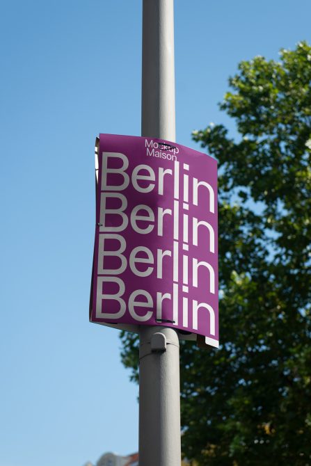 Outdoor banner mockup on a pole with the word Berlin repeated, clear sky background, ideal for designers to showcase advertising designs.