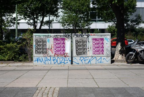 Urban street mockup with posters and graffiti on a metal box for designers looking to showcase their graphics in a realistic setting.