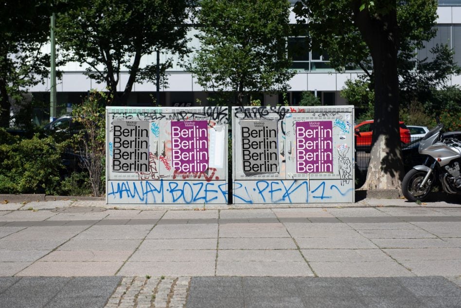 Dual posters on weathered wall with magenta type, covered in various street art markings