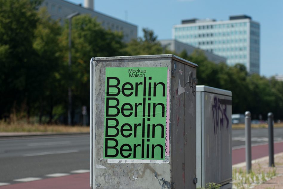 Worn electrical box displaying lime green poster with stacked Berlin typography