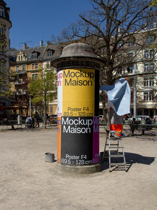 Urban outdoor poster mockup on advertising column with person applying poster, suitable for designers to showcase work.