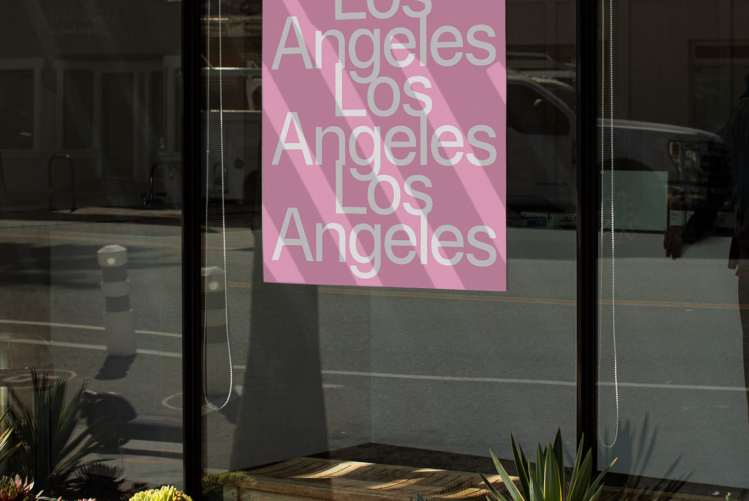 Urban storefront window poster mockup with repetitive Los Angeles text design, reflecting street scene, ideal for city branding graphics.