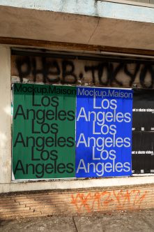 Boarded-up storefront with green plus blue poster mockup showing Los Angeles text pattern