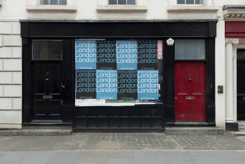 Black storefront mockup with text overlays and red door for urban shopfront design, perfect for graphics and templates.