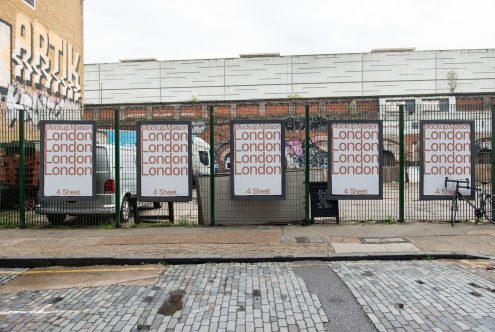 Urban poster mockup on a metal fence with a city backdrop for graphic designers displaying advertising design templates in a real-world setting.