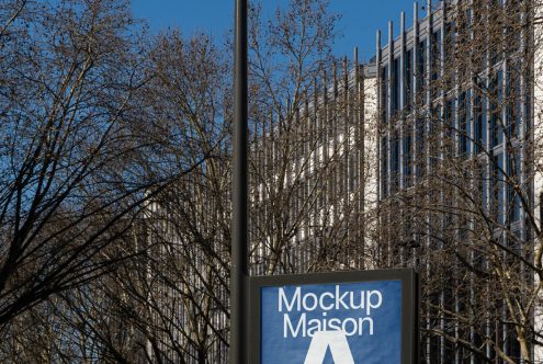 Urban billboard mockup with clear sky, leafless trees, and modern building, ideal for designers' advertising presentations.