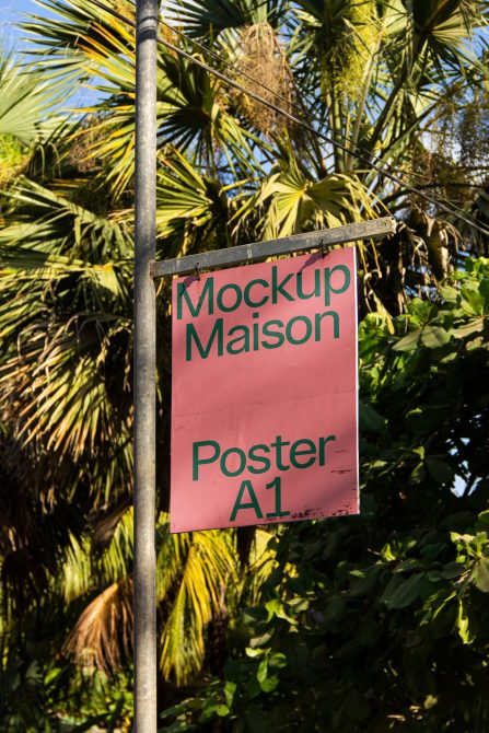 Pink poster mockup hanging on pole with tropical plants in the background, A1 size display for design presentation.