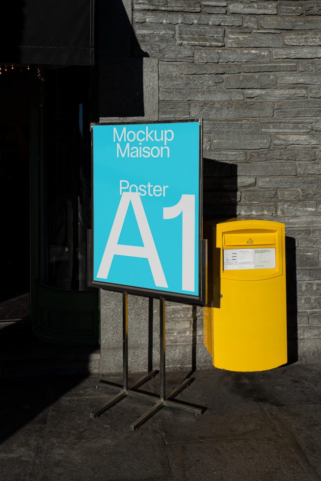 Outdoor poster mockup on sidewalk display stand for advertising design presentation, urban setting with stone wall background.