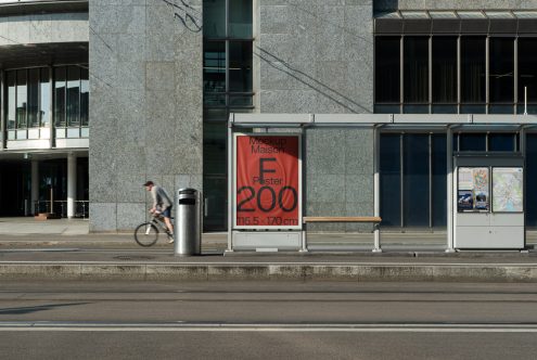 Urban bus stop with mockup poster display for advertising, clear sunny day, cyclist passing by, ideal for designers creating mockups.