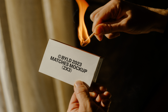 Person igniting match from a box with text, realistic packaging mockup for product design display.