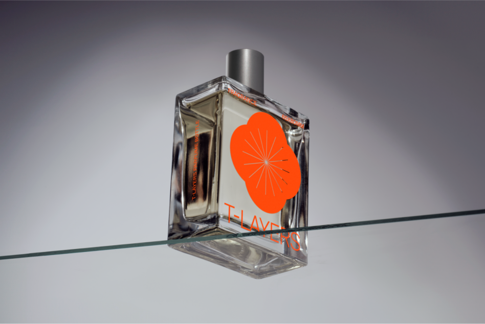 Perfume bottle mockup with bright orange geometric design on glass, balanced on wire against neutral backdrop