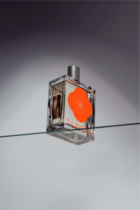 Minimalist fragrance bottle mockup with bright orange citrus slice label balanced on glass rod