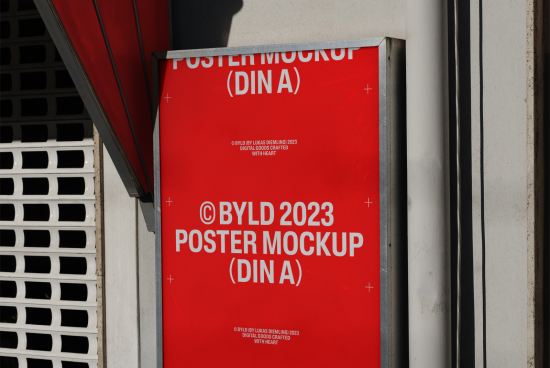 Mockup category: Poster mockup attached to outdoor wall, bright red design with sample text, clear shadows, realistic urban setting for designers.