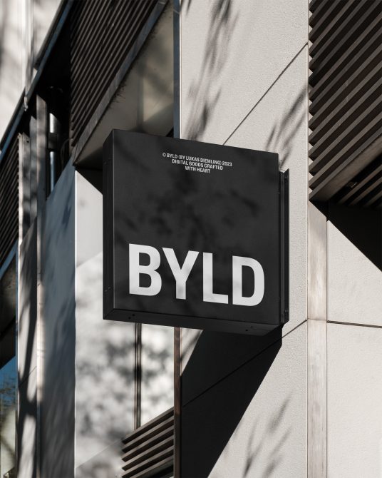 Black signage mockup with modern bold font, suspended on a building exterior in daylight, showcasing a crisp, urban look for design branding.