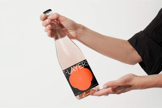 Hand holding a clear bottle with a stylish label design mockup, perfect for showcasing label graphics and branding designs.