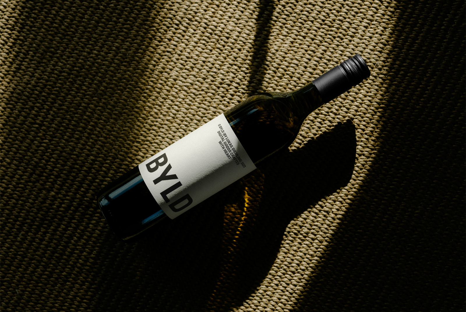 Elegant wine bottle mockup lying on textured fabric, with dramatic lighting and shadow play, ideal for showcasing label designs.