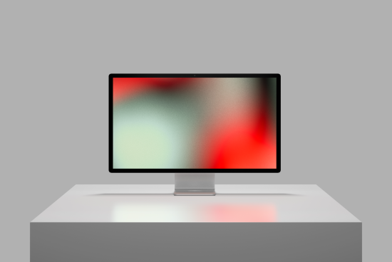 Modern computer monitor mockup on a gray stand and background showcasing a blurred colorful graphic design, ideal asset for template presentations.