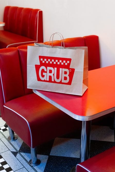 Grub branded shopping bag sitting on a retro red diner booth table