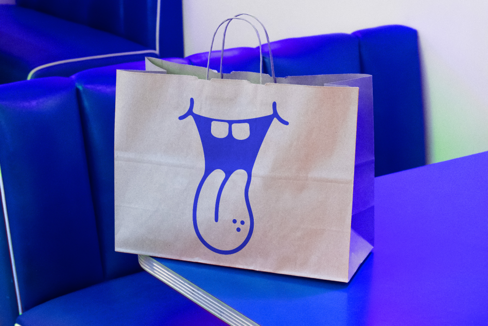 Paper shopping bag mockup with blue abstract artwork on a vibrant background, ideal for presentations and branding design.