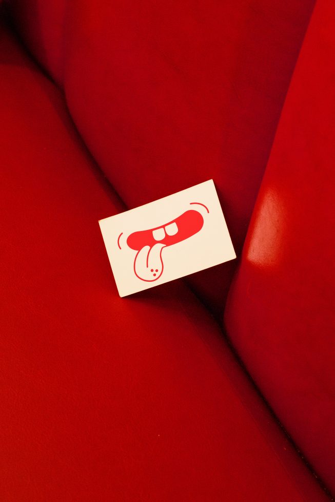 Business card mockup with red dog nose illustration on red couch, creative design presentation, graphic design asset.